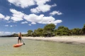 pływanie na czerwonej desce SUP Monster blisko greckiej plaży z linią drzew w tle