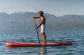 addler stojący bokiem na desce SUP Aqua Marina Monster na jeziorze w otoczeniu gór