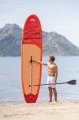 mężczyzna prezentuje pionowo ustawioną deskę SUP Aqua Marina Monster 12 na piaszczystej plaży