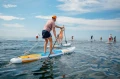 Pompowane deski SUP Gladiator Elite - duża grupa osób na wodzie w słoneczny dzień_half.webp