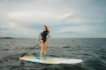 kobieta na desce SUP Gladiator Elite pływa na otwartym morzu w spokojnych warunkach.webp