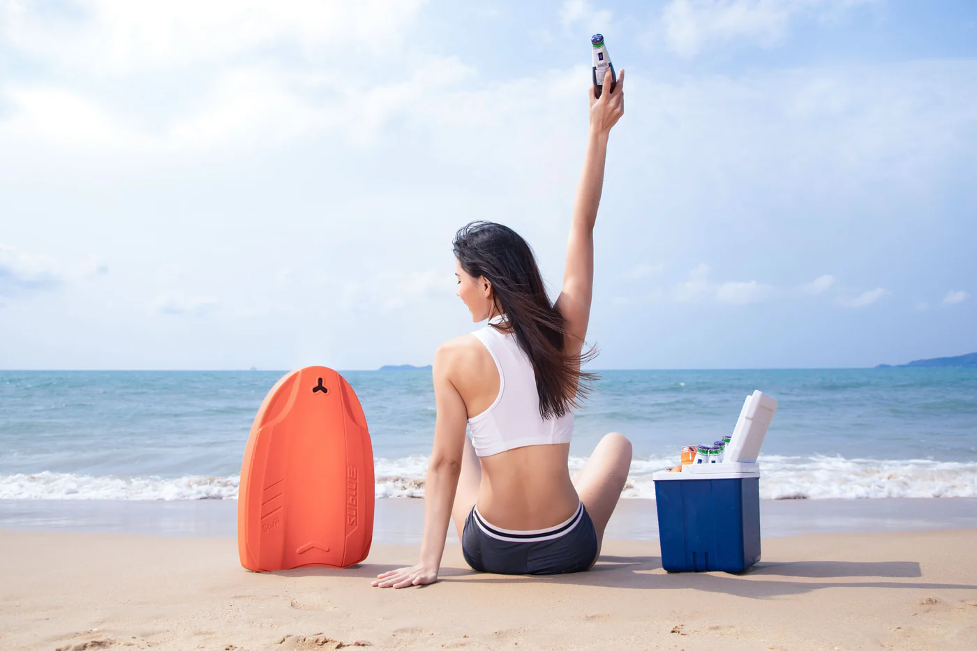 Deska do pływania elektryczna Swii - zdjęcie lifestyle na plaży dziewczyna z leżącą obok deską
