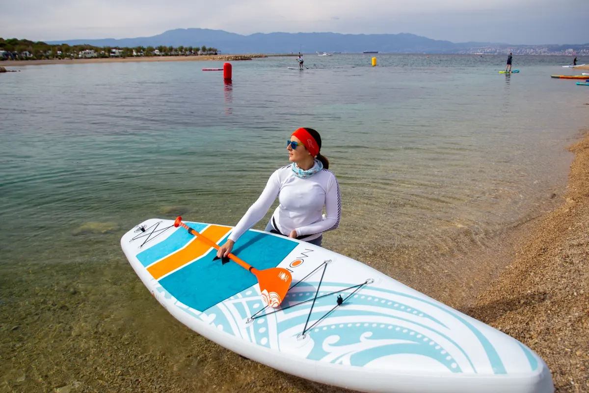 Deska SUP touring MOAI 12.6 na brzegu – przygotowanie do pływania na spokojnej zatoce